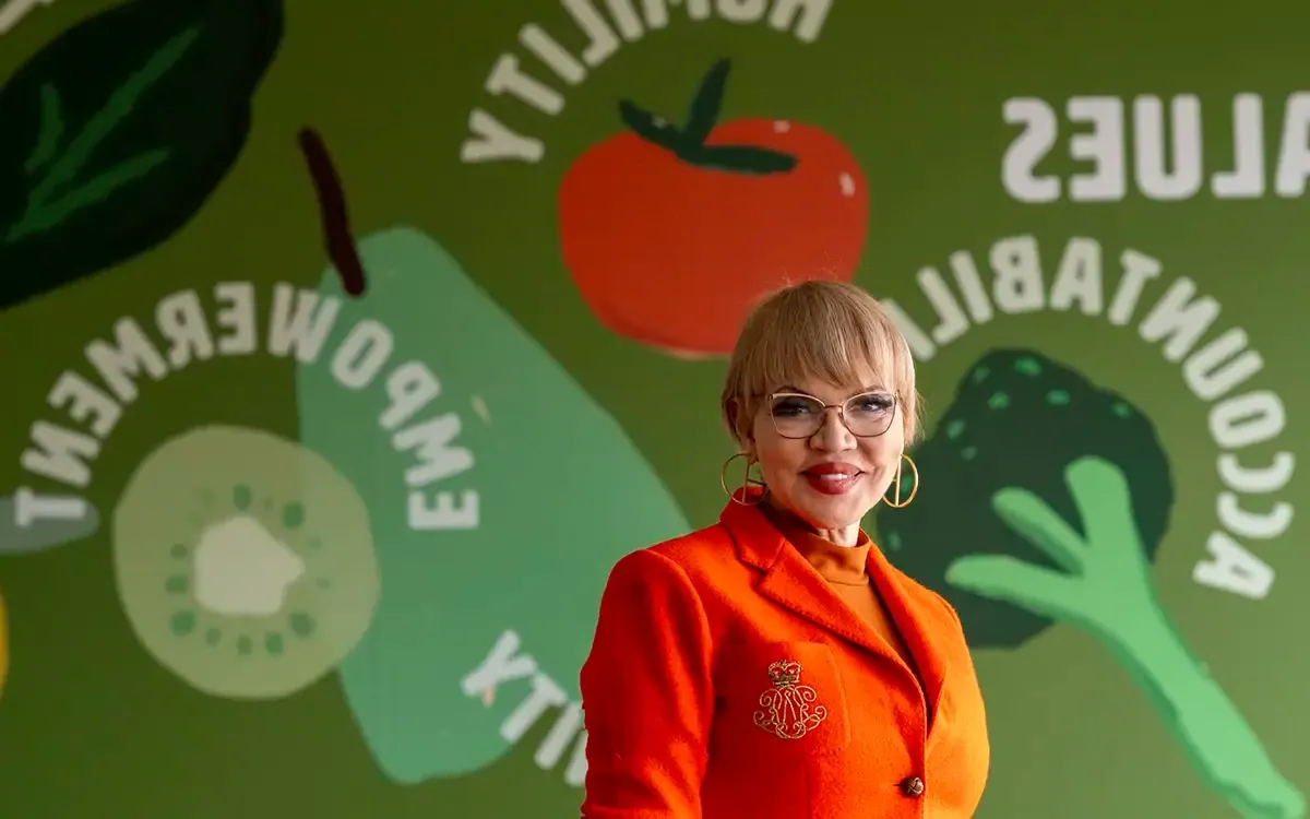 2024年Laetare奖得主Claire Babineaux-Fontenot, 穿着橙色的西装, 站在一堵五颜六色的墙前.